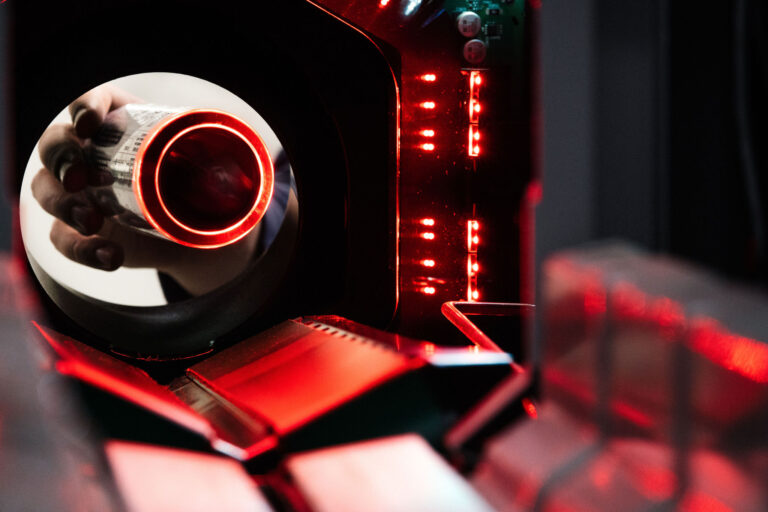 Juomapakkausten palautusautomaatin sisältä otetussa valokuvassa näkyy, kuinka joku on palauttamassa juomatölkkiä.